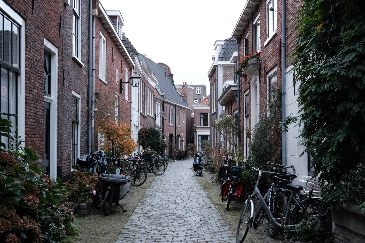 Bicycles along a narrow cobbled street between brick houses