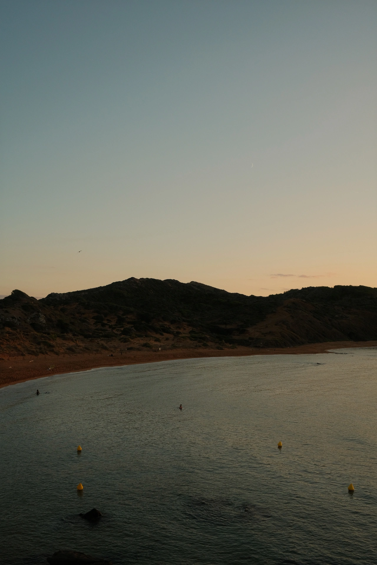 Soft evening light above a quiet bay and low hills