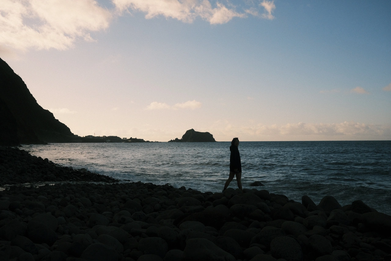 A distant silhouette on a rocky shoreline under an open sky