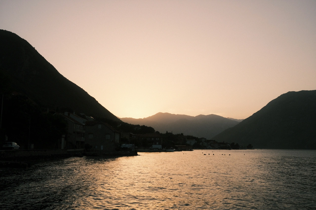 Amber sunset between mountains, reflected across a still bay