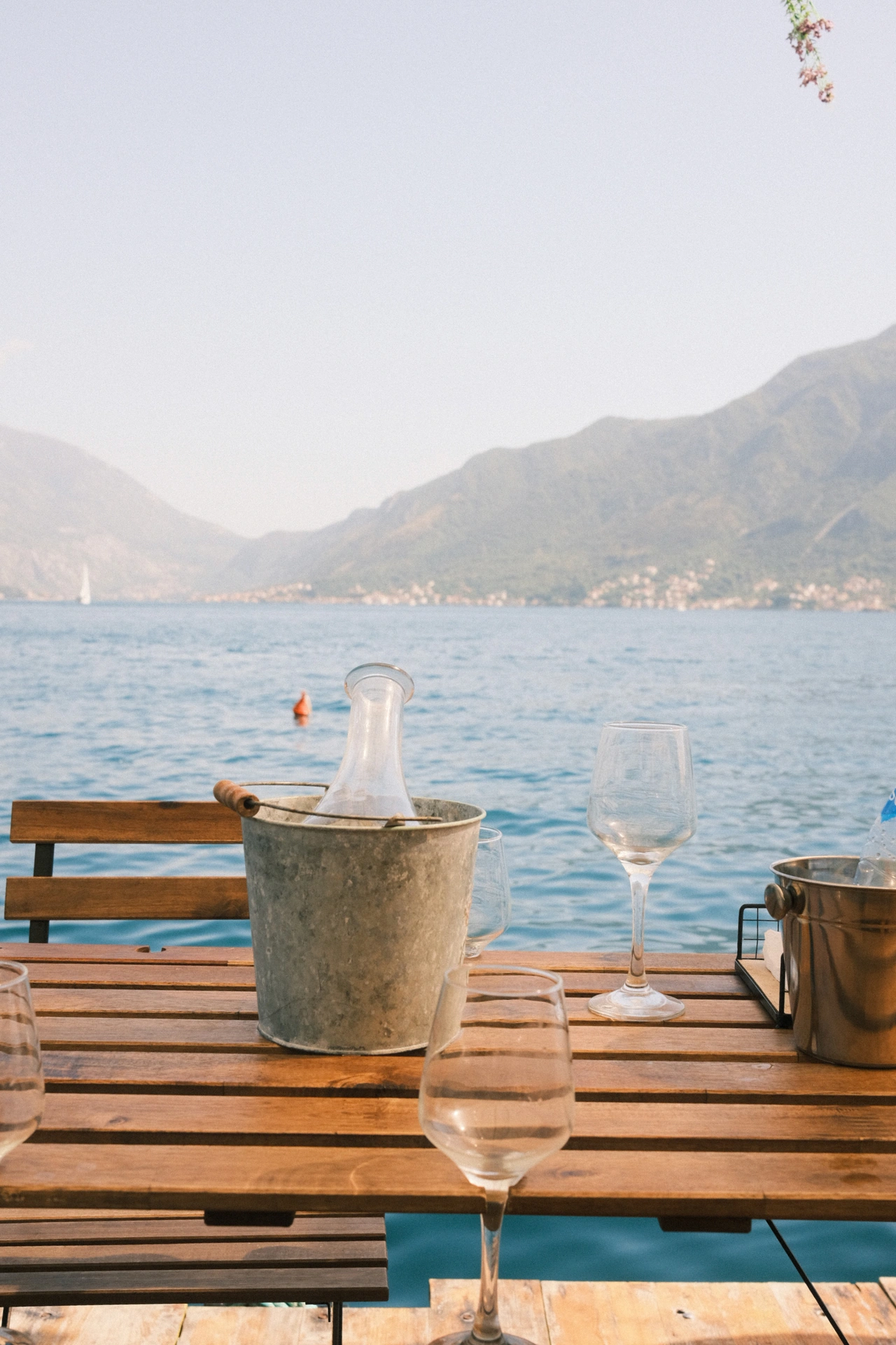 Wine glasses on a wooden table overlooking a mountain bay
