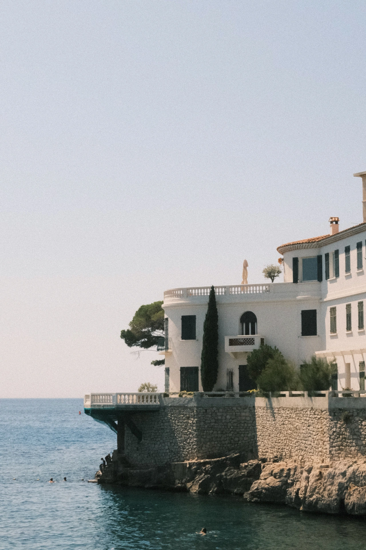 A white house and stone wall meeting the sea