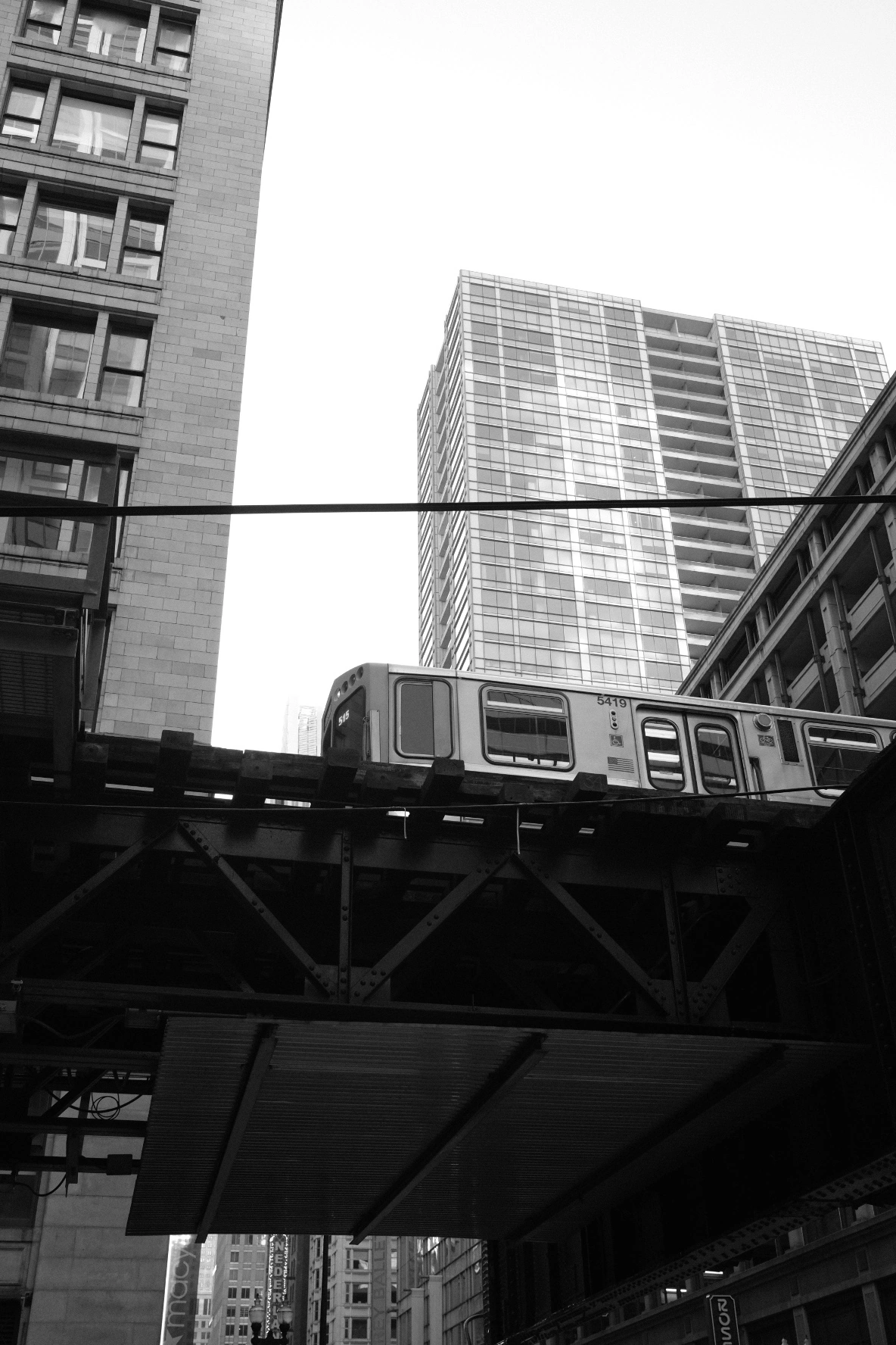 A train crossing between angular city towers, in black and white